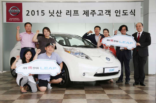 타케히코 키쿠치 한국닛산 대표(사진 오른쪽)가 제주 고객 대표들에게 리프를 전달하고 기념촬영을 하고 있다. <한국닛산 제공>